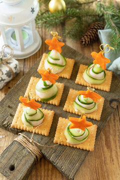 Naklejki New year meal idea Creative appetizers christmas. Christmas trees of ham, cucumber, cheese and star of carrot on crackers on the rustic table.