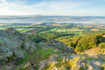 A view of misty countryside in Shropshire, UK with a rocky foreground  taken from the summit of the Wrekin hill in landscape orientation