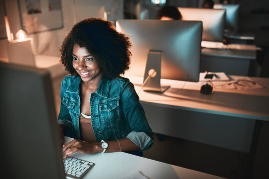 Night, black woman and typing in office for review, happy and excited for career opportunity. Dark, web designer and smile at tech for market research, growth or feedback in target audience forum