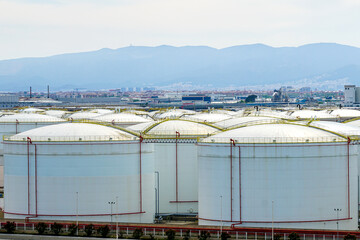 Many large round white reservoirs of chemical products in the port industrial terminal