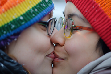 two young women kissing as a sign of love, wool hat with rainbow colors, lgtbq+, lgtb, lgtb, pride day, close-up, horizontal