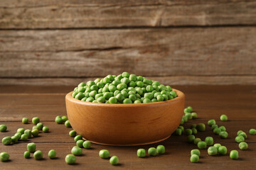 Fresh green peas in bowl on wooden table