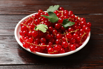 Fresh red currants and leaves on wooden table, closeup