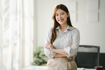 Businesswoman is calculating annual income and expenses at her office. Smiling female employee using laptop in modern office Copy space