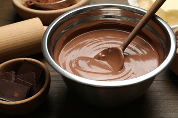 Chocolate dough in bowl and ingredients on wooden table, closeup