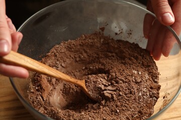 Woman making chocolate dough at table, closeup
