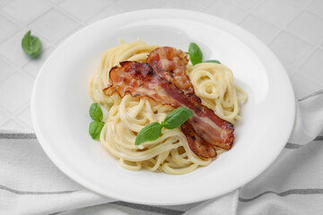 Delicious pasta Carbonara with bacon and basil on white tiled table, closeup
