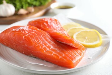 Pieces of fresh salmon with salt and lemon on white table, closeup