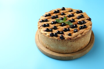 Delicious homemade blueberry pie with mint on light blue background, space for text