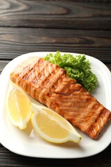 Delicious grilled salmon fillet served on wooden table, closeup