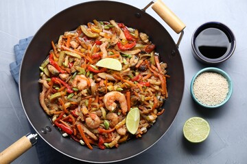 Stir-fry sea food in wok served on grey table, flat lay