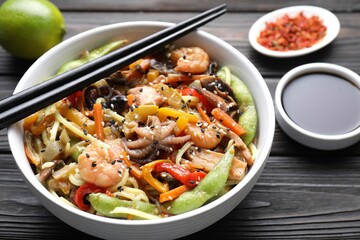 Stir-fry noodles with sea food served on wooden table, closeup
