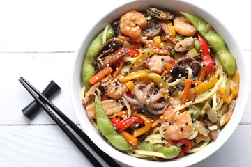 Stir-fry noodles with sea food served on white wooden table, flat lay