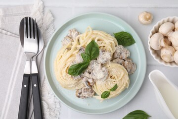 Delicious pasta with mushrooms and basil served on white tiled table, flat lay