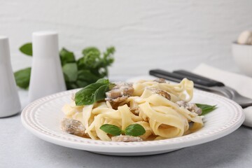 Delicious pasta with mushrooms and basil on light table, closeup