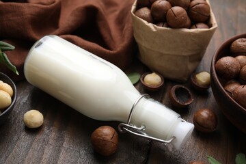 Bottle of macadamia milk and nuts on wooden table, closeup