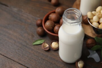 Bottle of macadamia milk and nuts on wooden table, closeup. Space for text