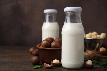 Bottles of macadamia milk and nuts on wooden table. Space for text