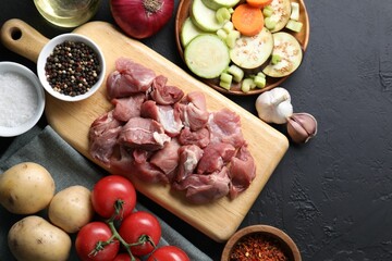 Cooking stew. Uncooked meat and vegetables on black table, flat lay