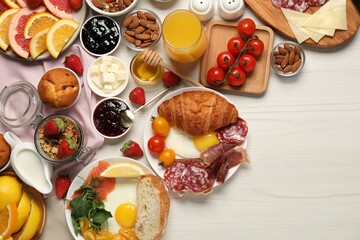 Different tasty food served for brunch on white wooden table, flat lay. Space for text