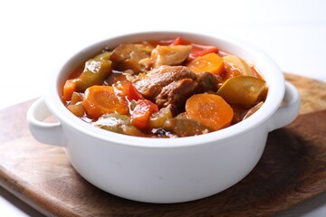Delicious stew with vegetables in bowl on white table, closeup