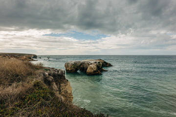 Montana de Oro, California. Rocks along the shore and dramatic cloudy sky in the background.