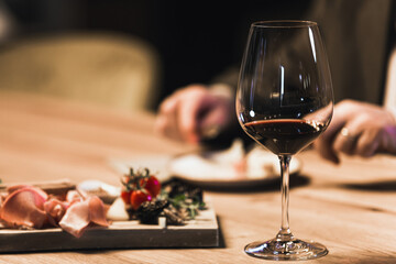 People drinking wine and eating cold cut meat in a wine cellar.