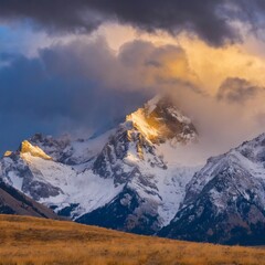 Dramatic snow-capped peaks with storm clouds gathering above, creating a powerful winter scene