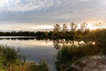 Beautiful lake for fishing illuminated by the warm sunset light on an overcast fall day. Concept of...