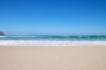 Welle am Strand bei blauem Himmel