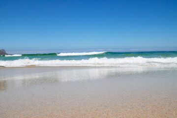 Welle am Strand bei blauem Himmel