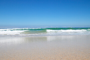 Welle am Strand bei blauem Himmel
