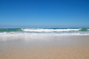 Welle am Strand bei blauem Himmel