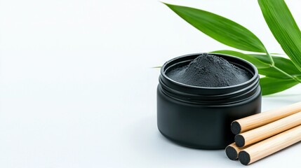   A jar of black powder with nearby bamboo sticks and green leaf on white background