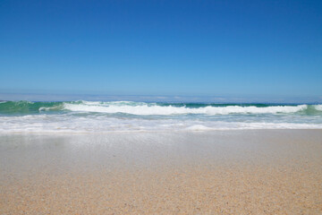 Welle am Strand bei blauem Himmel