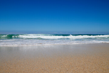 Welle am Strand bei blauem Himmel