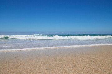 Welle am Strand bei blauem Himmel