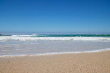 Welle am Strand bei blauem Himmel