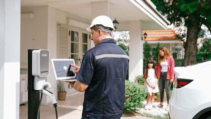 Qualified technician working on home EV charging station installation, making troubleshooting and configuration setup on charging system with empty laptop screem for EV at home. Synchronos