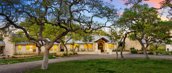 Obraz premium Charming ranch-style home surrounded by lush trees and a serene sunset in Texas