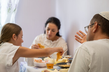 jewish family celebrating hanukkah, israel, boy in kippah, jewish holidays, yom kippur feast, table with food, honey, donuts, family holiday