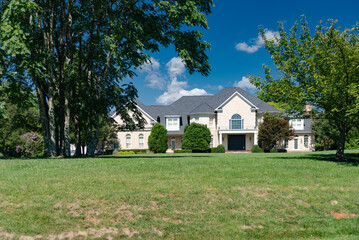 Landscape with large country house. Large mowed lawn and blue sky.