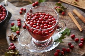 A cup of herbal tea with fresh wild hawthorn berries