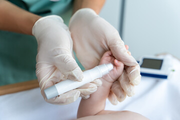 Nurse using glucometer on newborn baby to check his level of sugar in blood