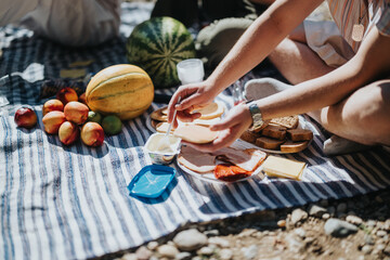 An inviting picnic scene with assorted fruits, sliced bread, and fresh ingredients on a striped blanket. Perfect for outdoor leisure activities under the sun.