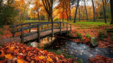 Obraz premium A small wooden bridge over a creek in a park, surrounded by colorful autumn leaves.