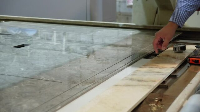 Experienced male quality control inspector examining and touching glossy surface of polished marble slab at quartz stone factory. Manufacturing kitchen countertop quartz