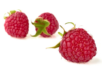 berries of ripe red raspberries with green stalks isolated on white table