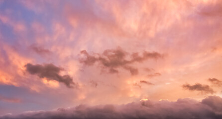 A beautiful sky tinted by the sun leaving vibrant shades of gold, pink, blue and multicolored. Clouds in the twilight evening and morning sky. Cloudy sky background in the evening, and during the day.