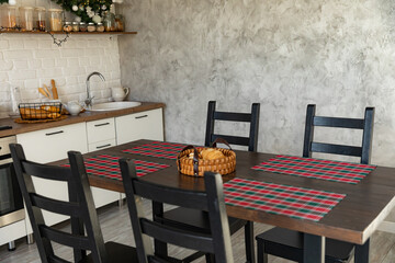 Festive winter cozy kitchen interior with garlands, decorations and gifts. Christmas dinner at the decorated table. Modern Kitchen Interior in New Luxury Home Decorated in Christmas Style